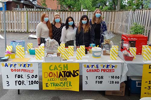 5 women standing behind a table during a fundraiser.