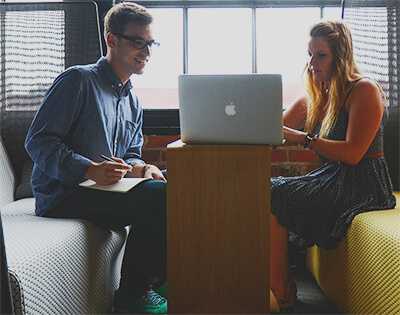 Man and woman having a casual meeting looking at a laptop.