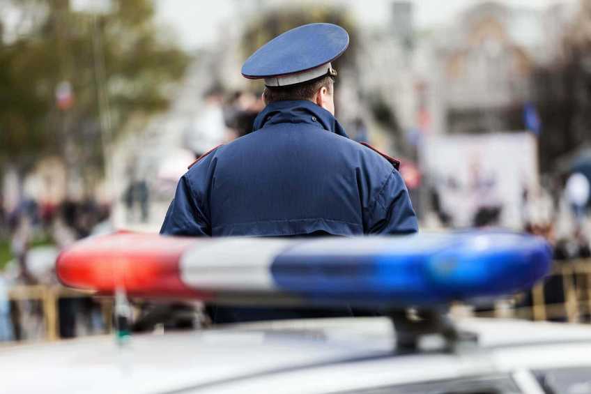 Police officer standing behind a police car.