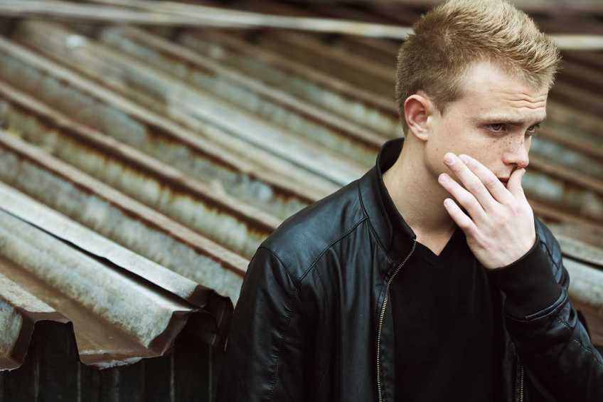 Young man with his hand on his face looking concerned.