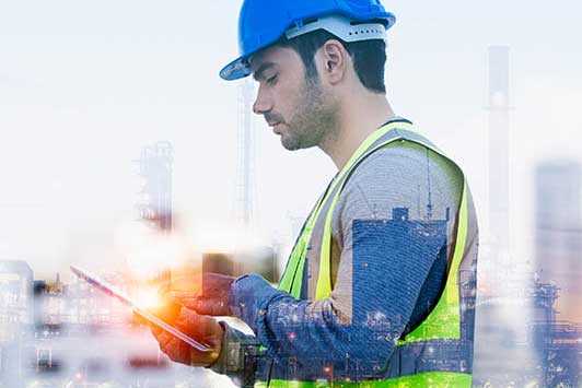 Construction worker in blue hard had looking at a tablet.