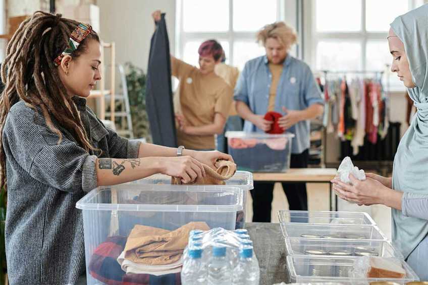 People standing at tables sorting donations in plastic bins.