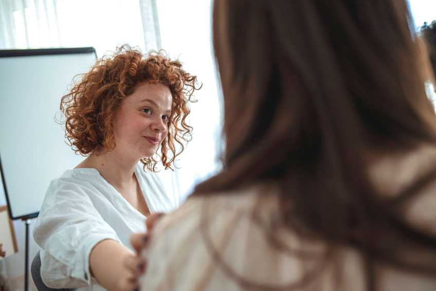 woman smiling with hand on shoulder of another woman