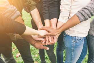 Group of people standing in a circle with hands joined.