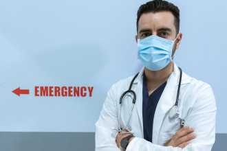 Doctor standing in front of Emergency Room sign. 