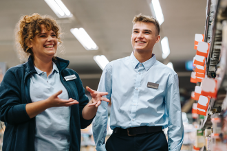 two retail workers, one women, one young man, smiling